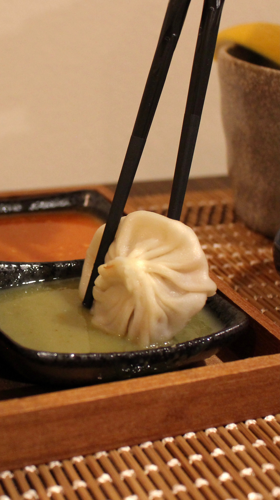 Dumpling lifted with chopsticks over LAN PRIK sauce