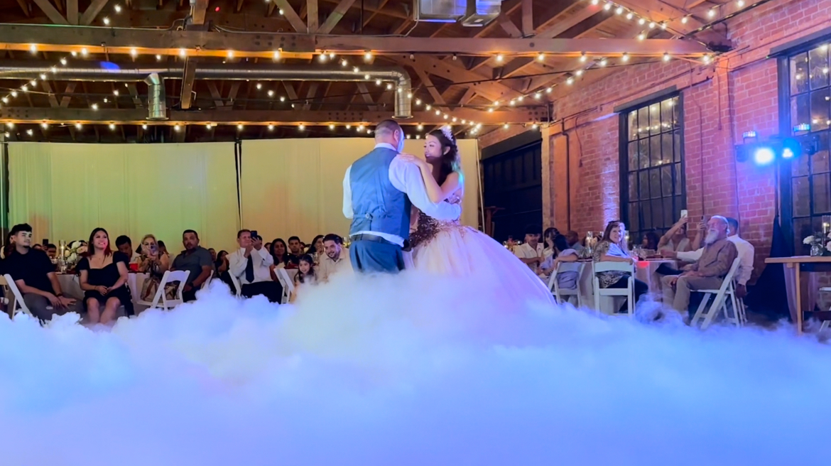 First dance on a fog-covered floor under warm event lighting